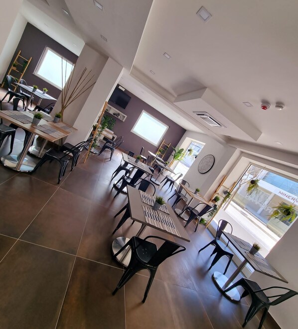 A spacious dining area with multiple tables and chairs, large windows providing natural light, and a modern interior design. - HOTEL CRISVAN (Rimini)
