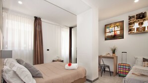 A hotel room with a bed, a desk, a chair, a suitcase, and a wall-mounted artwork. - HOTEL CRISVAN (Rimini)