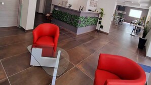 A modern reception area with a green wall, a reception desk, and two red chairs. - HOTEL CRISVAN (Rimini)