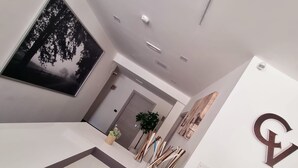 A modern interior with a large black and white tree painting, a minimalist design, and a prominent 'E' logo on the wall. - HOTEL CRISVAN (Rimini)