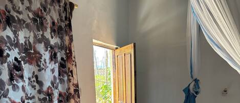 A room with a wooden door, a small white stool, and a curtain with a floral pattern.