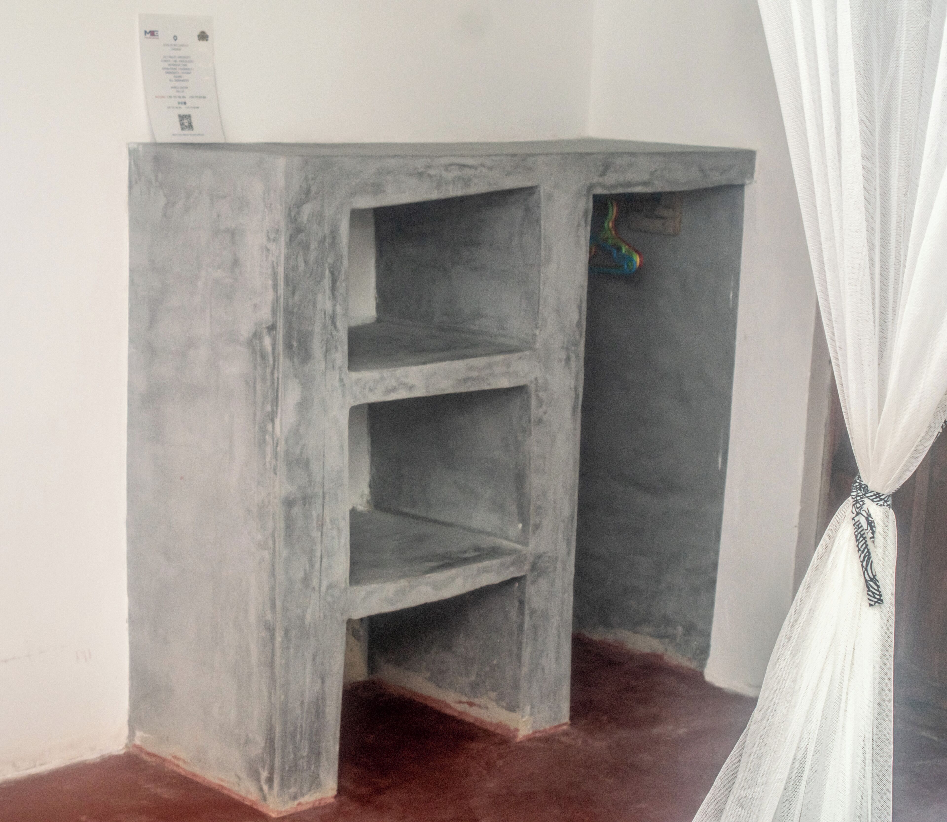 A corner desk with a shelf, a hanging toy, and a curtain.