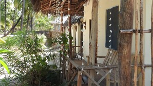 Une construction rustique à toit de chaume, avec des poutres en bois et un escalier en bois menant à une porte.