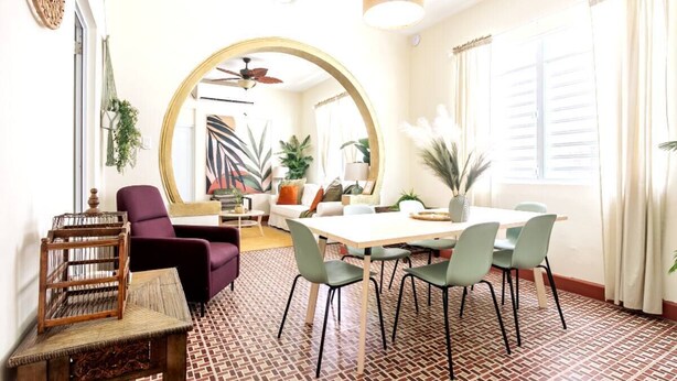 A modern living room with a dining area, featuring a round mirror, a ceiling fan, and a patterned floor. - 610@Miramar- up to 40 people (San Juan)