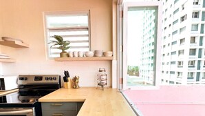 A modern kitchen with a wooden countertop, stainless steel appliances, and a window overlooking a high-rise building. - 610@Miramar- up to 40 people (San Juan)
