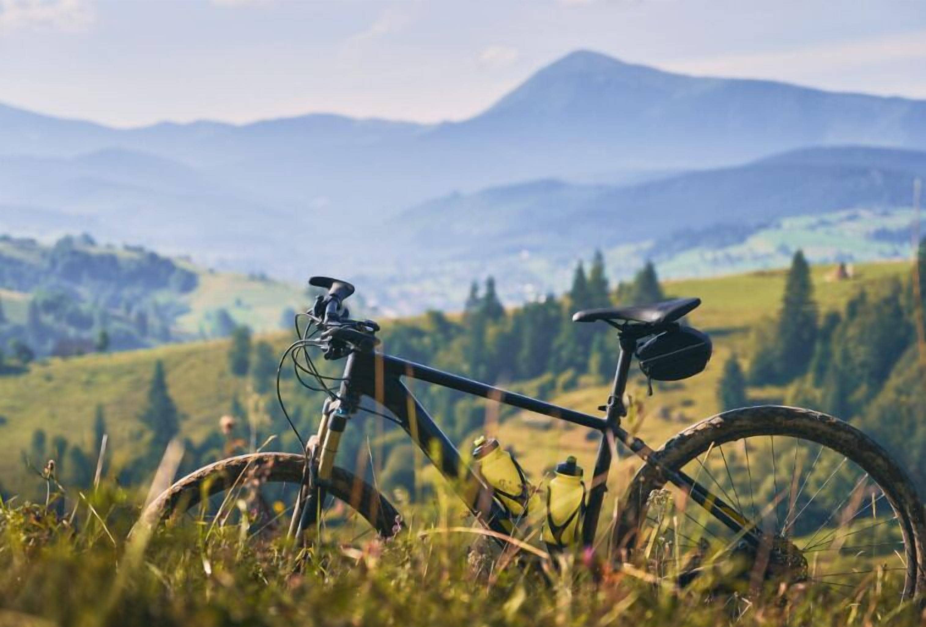 A bicycle parked on a grassy hill with a mountainous landscape in the background.