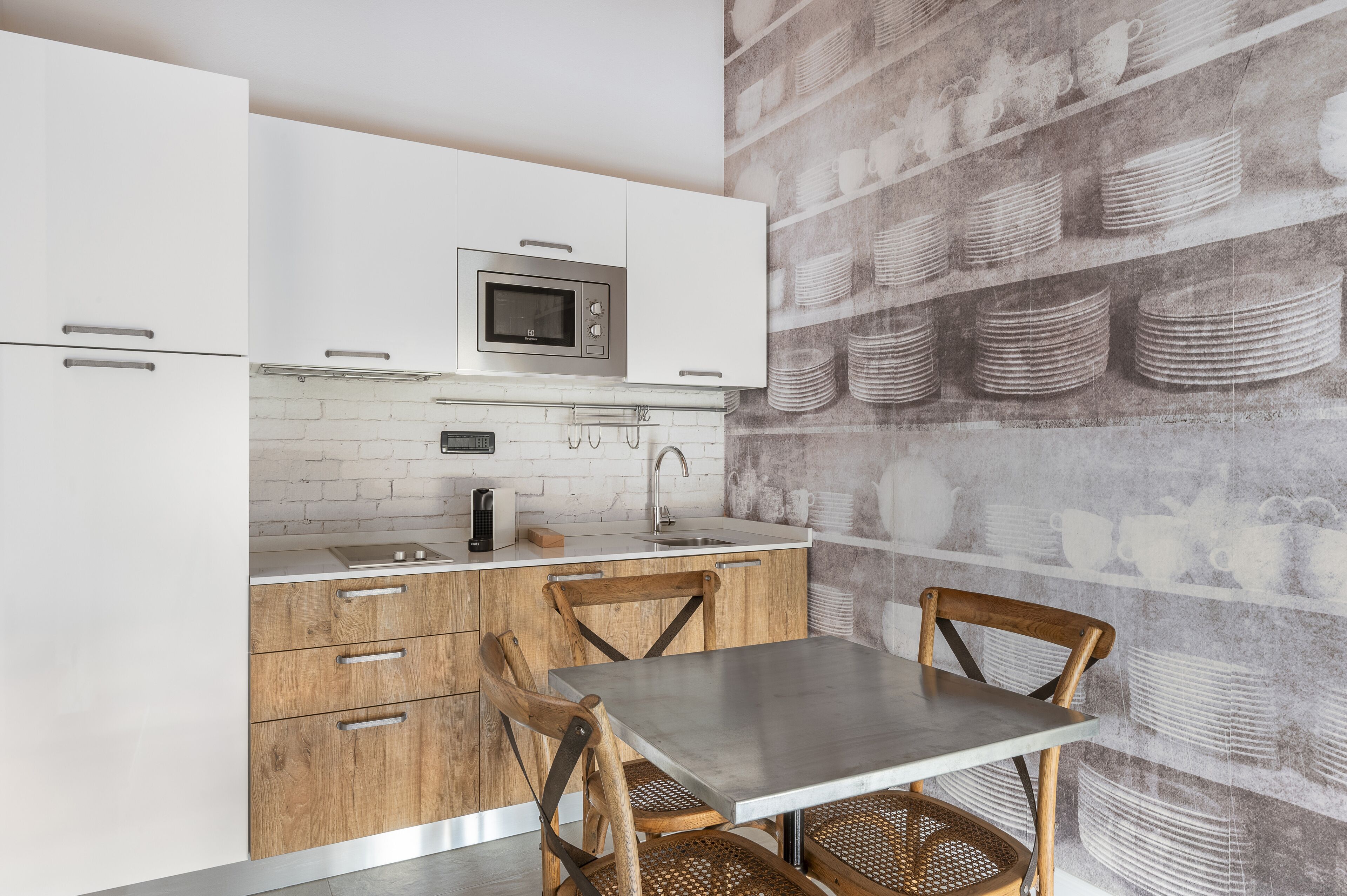 A modern kitchen with white cabinets, a stainless steel microwave, and a wooden table with chairs.