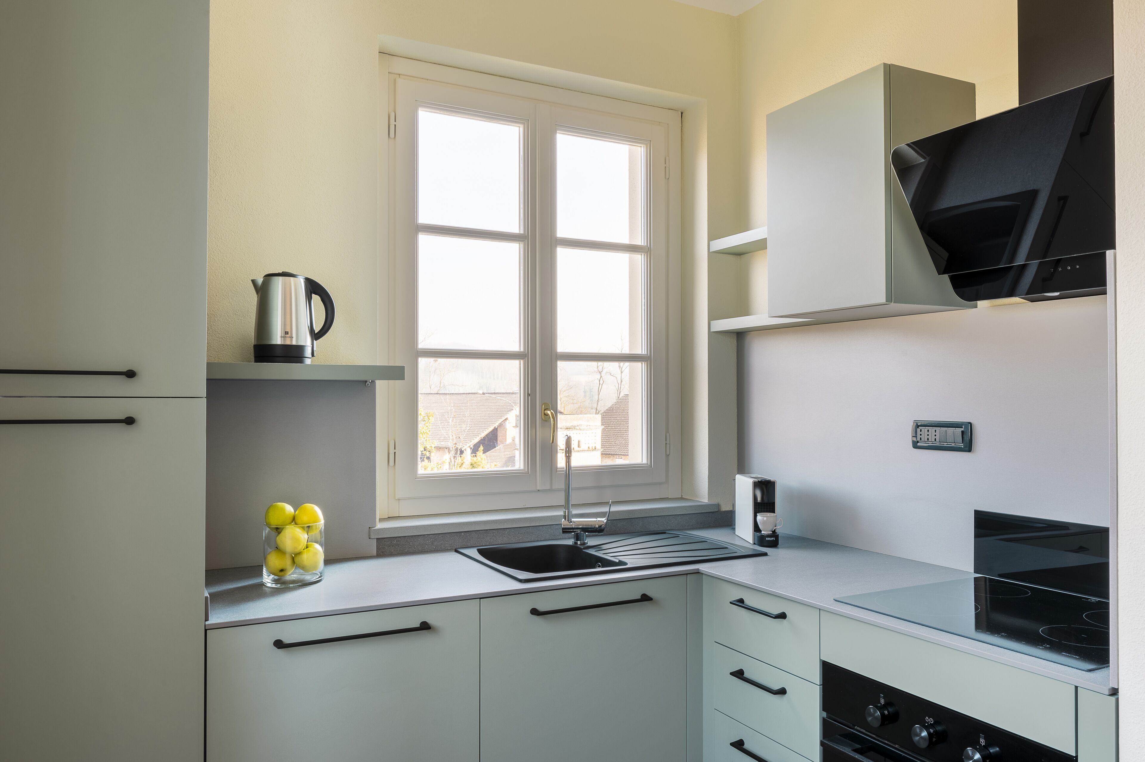 A modern kitchen with a window, stainless steel appliances, and a built-in oven.