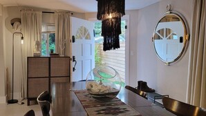 A modern dining area with a glass table, a decorative bowl, and a round mirror on the wall.