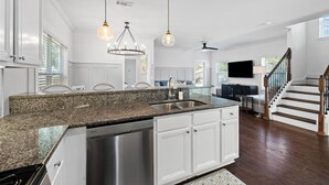 Una cocina moderna con encimeras de granito, electrodomésticos de acero inoxidable e iluminación colgante.