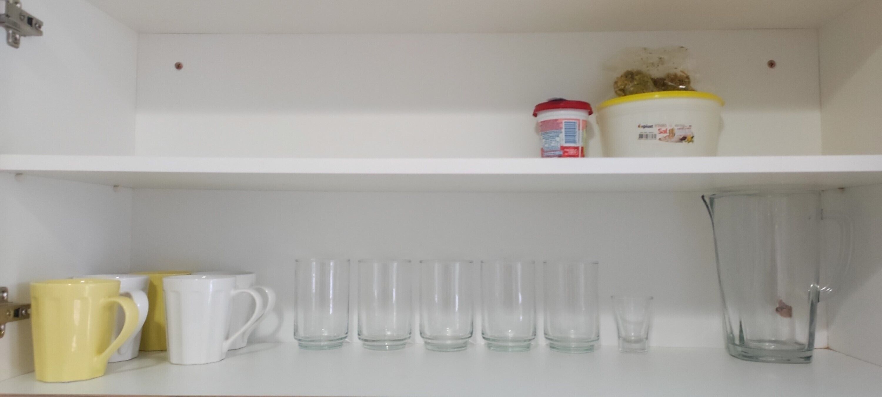 Une étagère blanche avec un récipient et une tasse.