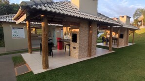 A covered outdoor seating area with a grill, a trash bin, and a signboard. - HotFérias Flat Enseada pesca permitida (Caldas Novas)