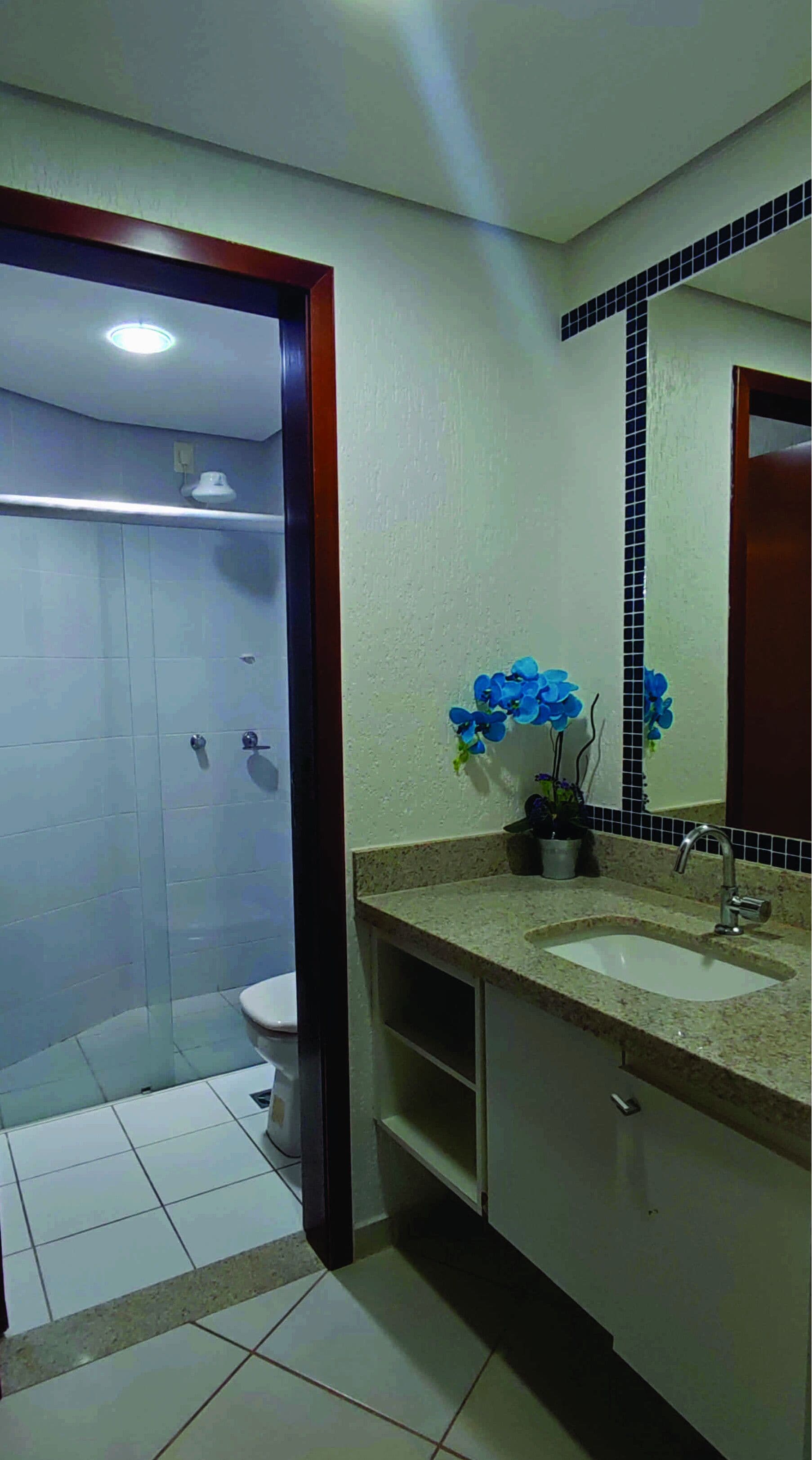 Un baño con ducha, inodoro, dos lavamanos y un espejo.