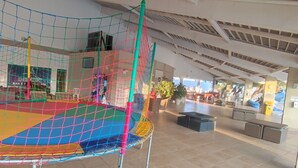 A netted play area with colorful flooring and a high ceiling with exposed beams. - HotFérias Flat Enseada pesca permitida (Caldas Novas)