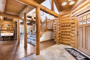 L’intérieur d’une cabane en rondins, avec un sol carrelé en pierre, un escalier en bois et un banc.