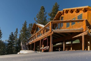 Une cabane en bois dotée d’un balcon, entourée d’arbres.