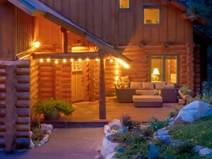 Une cabane en rondins dotée d’un porche couvert, de sièges extérieurs et d’une entrée bien éclairée.