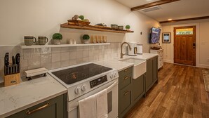 A kitchen with a stove, sink, and wooden shelves with decorative items.
