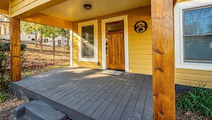 A wooden porch with a dark wooden deck, two doors, and a small window.