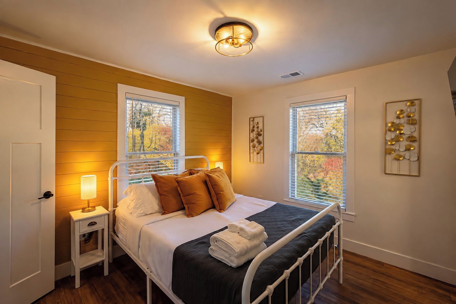 A bedroom with a bed, bedside tables, a lamp, and a window with blinds.