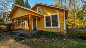A yellow house with a porch, a window, and a door.