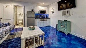 Un espacio habitable compacto con kitchenette, comedor y televisor montado en la pared.