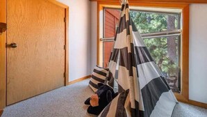 A cozy room with a wooden door, a window with a view of trees, and a striped canopy. - Stunning 3-Bed 2 Bath Cabin with Loft @ Northstar (Truckee)