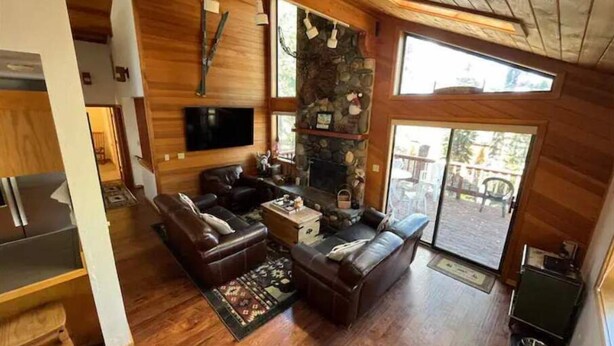 A cozy living room with a stone fireplace, leather sofas, and a television. - Stunning 3-Bed 2 Bath Cabin with Loft @ Northstar (Truckee)