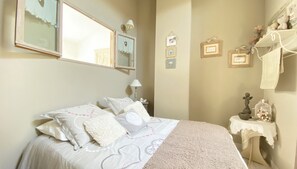 Un dormitorio con cama, mesita de noche, lámpara, espejo y adornos en la pared.