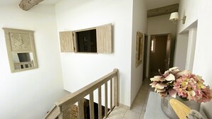 A staircase with a wooden railing, a wall-mounted mirror, and a vase with flowers. - Villa Provençale (La Cadière-d'Azur)