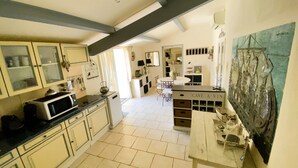 A kitchen with a microwave, cabinets, and a wine rack. - Villa Provençale (La Cadière-d'Azur)