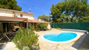 A backyard with a swimming pool, a patio with outdoor furniture, and a stone wall. - Villa Provençale (La Cadière-d'Azur)