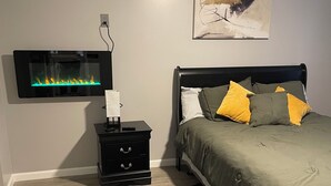 Een slaapkamer met een bed, nachtkastje, wandtelevisie en plafondventilator.
