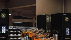 Una estación de café con máquinas de café FreshMorn, variedad de tazas y frascos con condimentos.