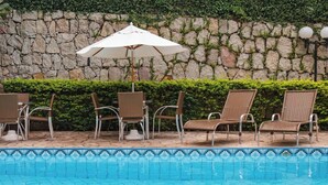 Ein Poolbereich mit Liegestühlen und einem weißen Sonnenschirm.
