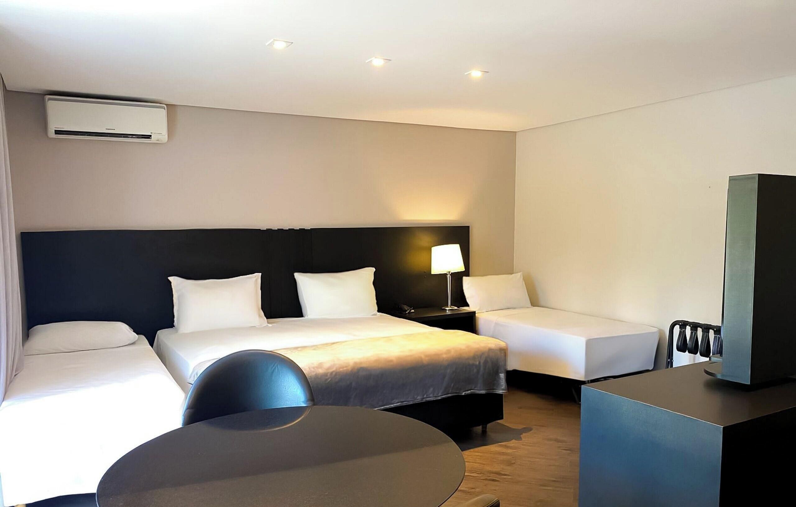 A hotel room with a bed, two bedside tables, a desk, and a chair.