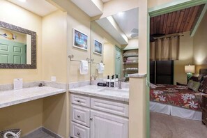 Un bagno con doppio lavabo, uno specchio e un letto con copripiumino floreale.