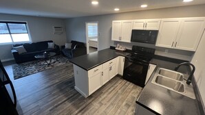 Una cucina moderna con mobili bianchi, piano cottura nero ed elettrodomestici in acciaio inossidabile.