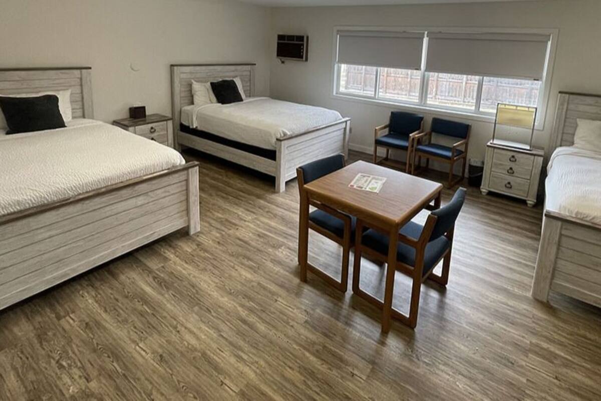Una habitación de hotel con dos camas, una mesita y dos sillas.
