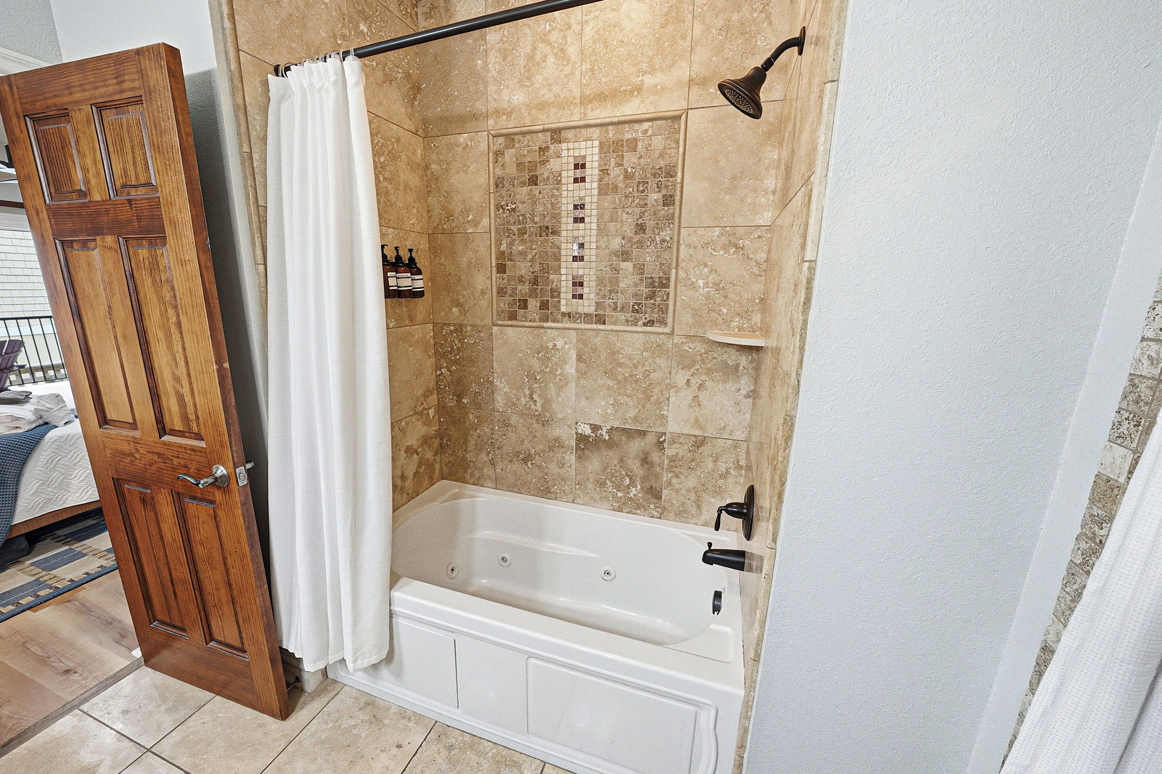 A bathroom with a bathtub, shower, and a wooden door.
