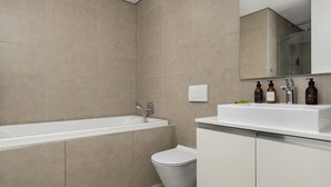 Ein modernes Badezimmer mit Badewanne, Toilette und Waschbecken.