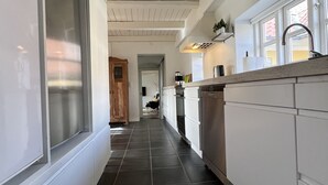 A kitchen with white cabinets, a black tiled floor, and a wooden ceiling. - Lake View Apartment (Grindsted)
