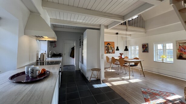 A spacious kitchen with a dining area, featuring a high ceiling and wooden beams. - Lake View Apartment (Grindsted)