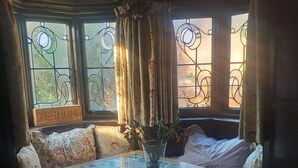 A cozy dining area with a tiled table, floral cushions, and a vase with flowers. - Jesmond vegan B&B  (Hull)