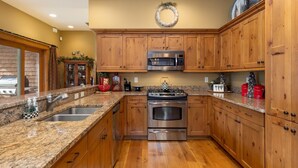 A kitchen with wooden cabinets, granite countertops, stainless steel appliances, and a decorative wreath on the wall. - Spacious Holiday Retreat in Keystone! (Keystone)