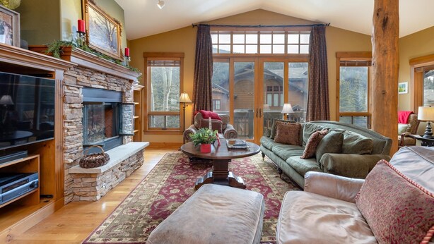 A cozy living room with a stone fireplace, a large window, and a comfortable seating area. - Spacious Holiday Retreat in Keystone! (Keystone)
