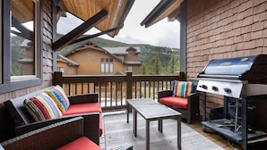 A covered outdoor area with wicker furniture, a grill, and a view of a mountain. - Spacious Holiday Retreat in Keystone! (Keystone)