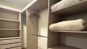 A walk-in closet with wooden shelving, drawers, and hanging space. - Aparts4Days Miraflores Down Town 1 or 3 Bedroom Apartment (Lima)