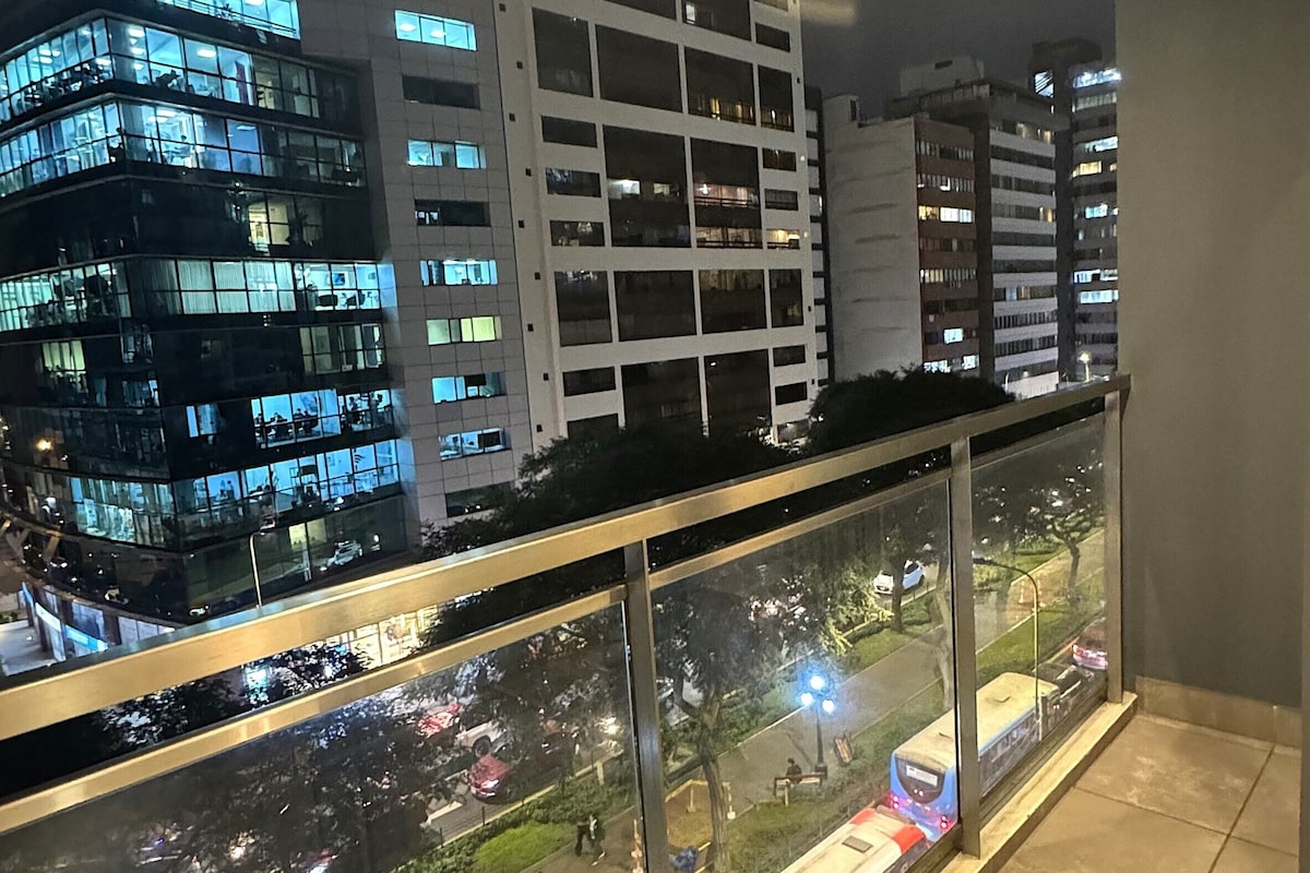 A balcony with a glass railing overlooking a cityscape at night.