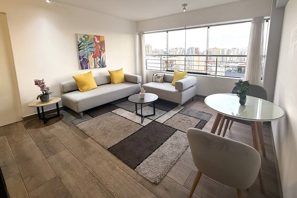 Un salon moderne comprenant un canapé, deux fauteuils, une table basse, une petite table d’appoint et une table à manger.